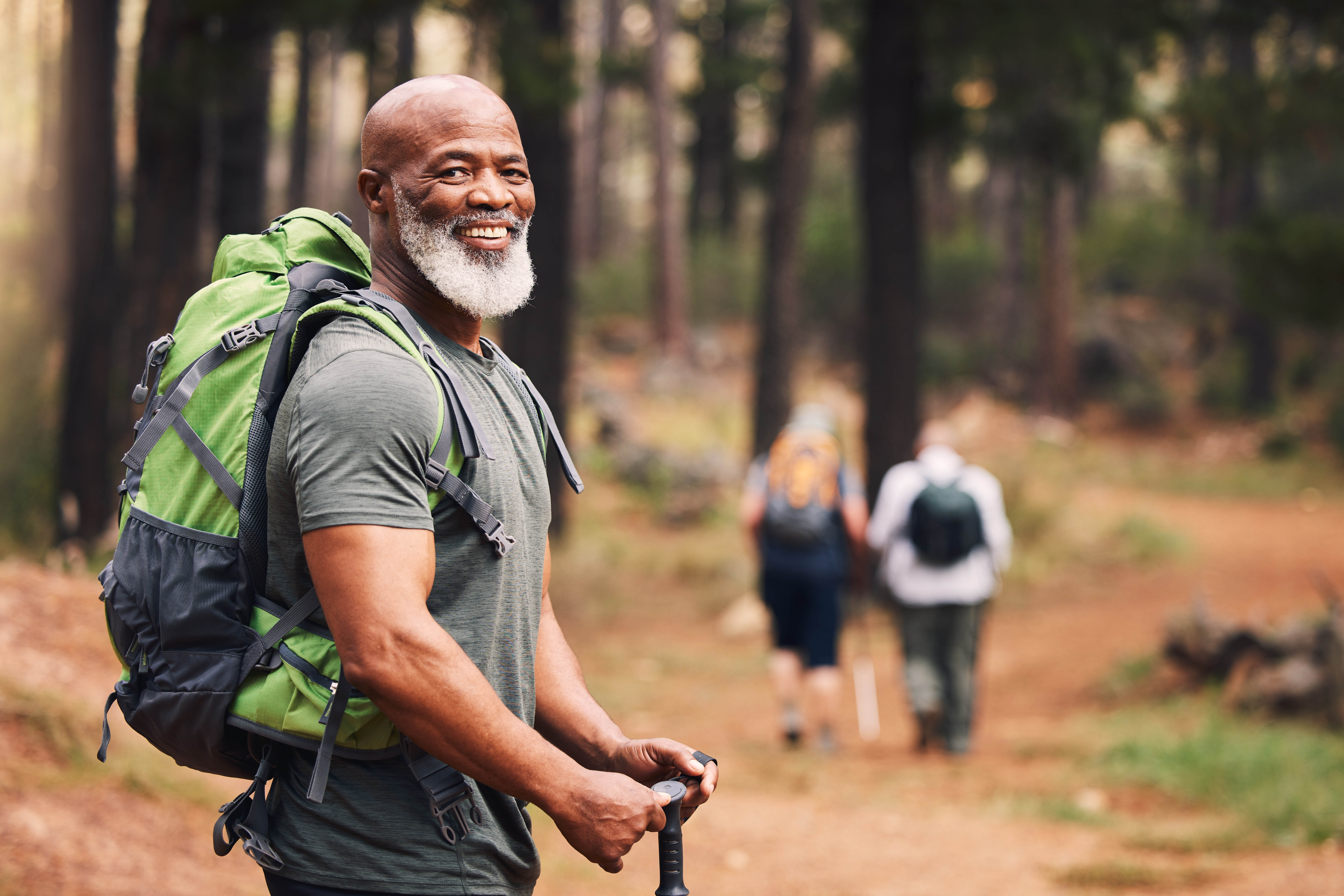 Older man hiking with a small group in a forest Older man hiking with a small group in a forest